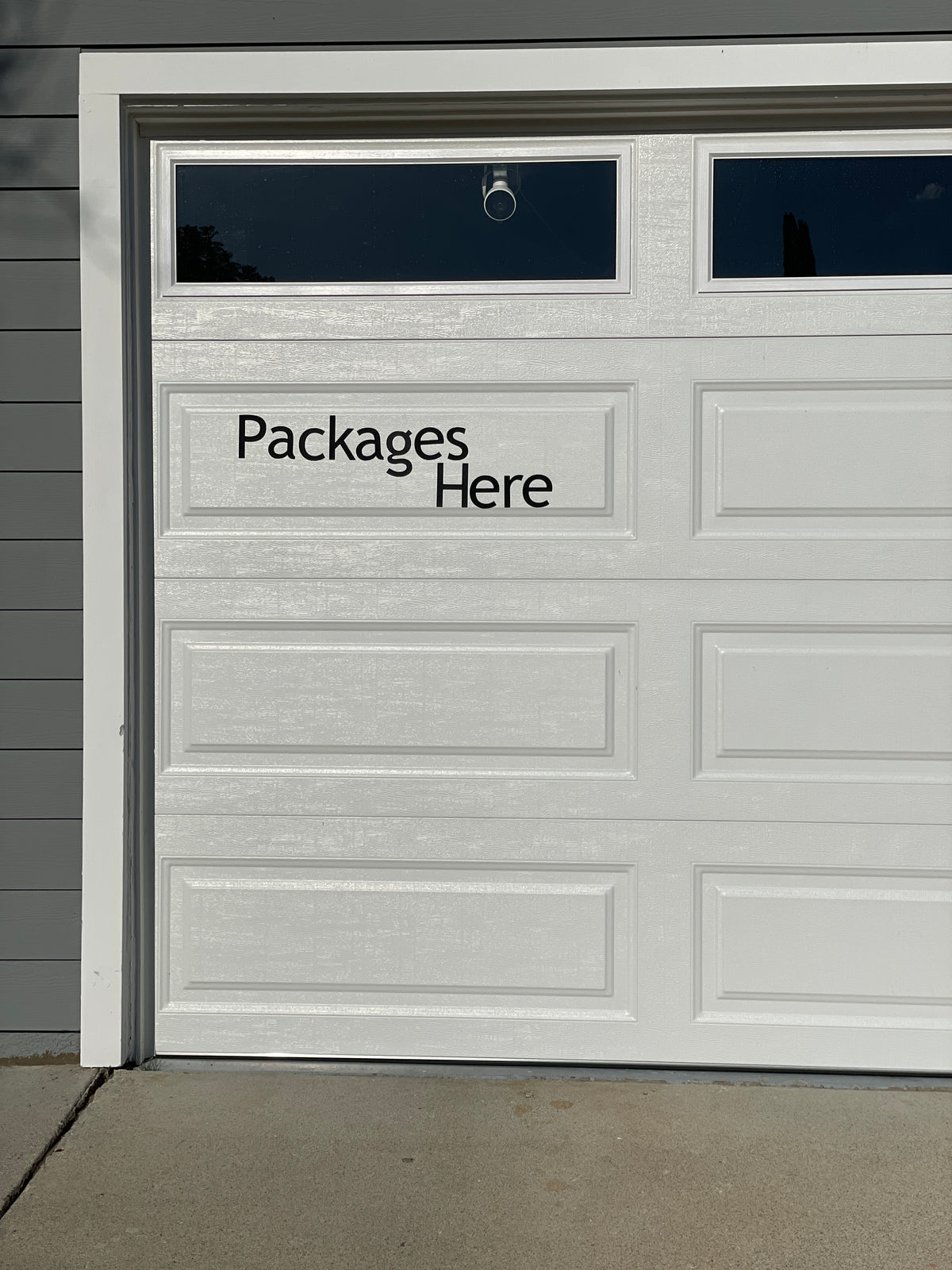 White garage door with "Packages Here" magnetic lettering